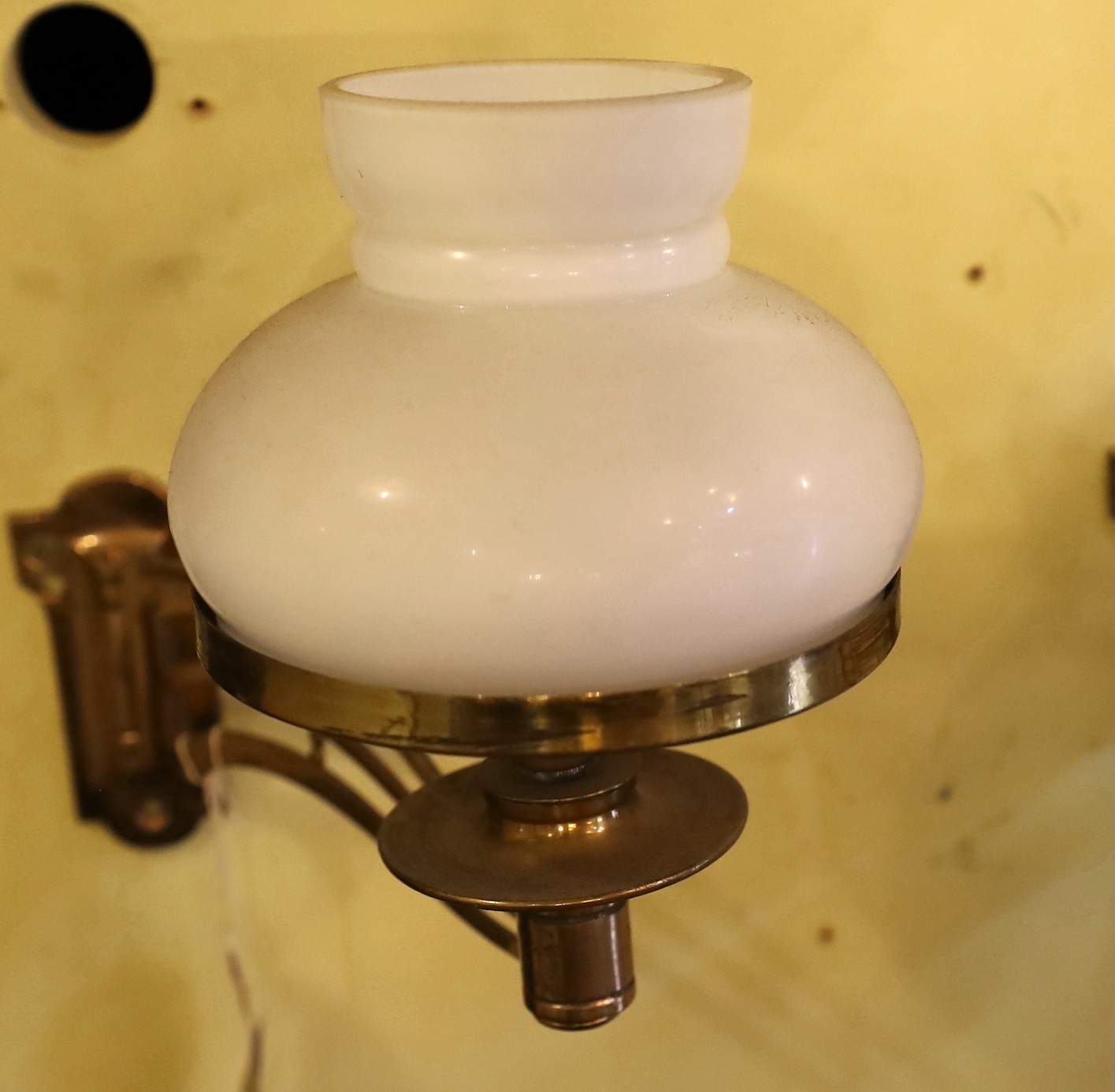 A pair of late Victorian brass swivelling wall lights with opaque glass shades, height 25cm. depth 25cm